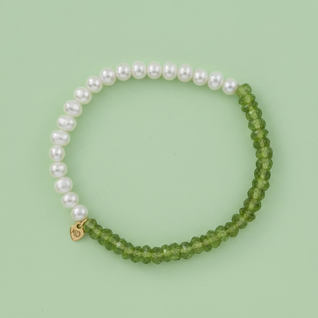 Bracelet with white pearls and green beads on a light gray background