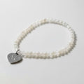 Pearl bracelet with a silver heart-shaped charm on a white background