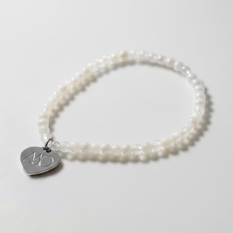 Pearl bracelet with a silver heart-shaped charm on a white background