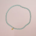 Turquoise beaded bracelet with a gold clasp on a beige background