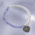 Pearl bracelet with heart-shaped charm on a glittery background