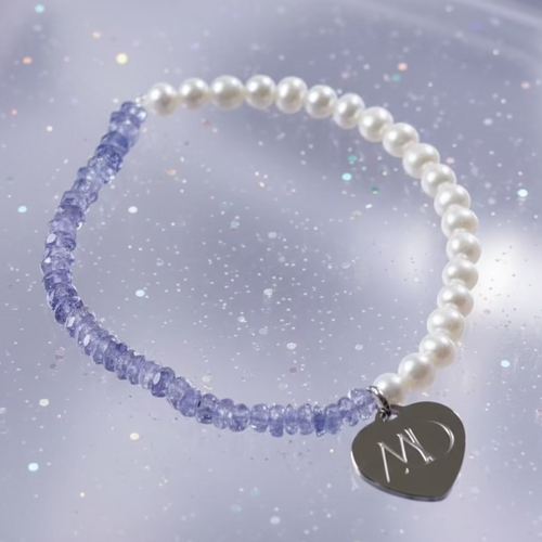 Pearl bracelet with heart-shaped charm on a glittery background