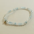 Beaded bracelet with a gold charm on a light gray background