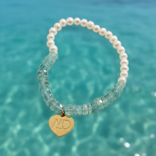 The Mermaid's Den bracelet with faceted blue aquamarine beads, white freshwater pearls, and a gold heart charm.