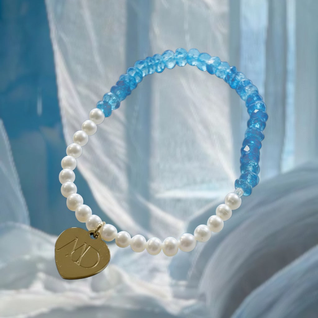 The Mermaid's Den Lobelia bracelet featuring faceted blue topaz beads, freshwater pearls, and a gold heart charm.