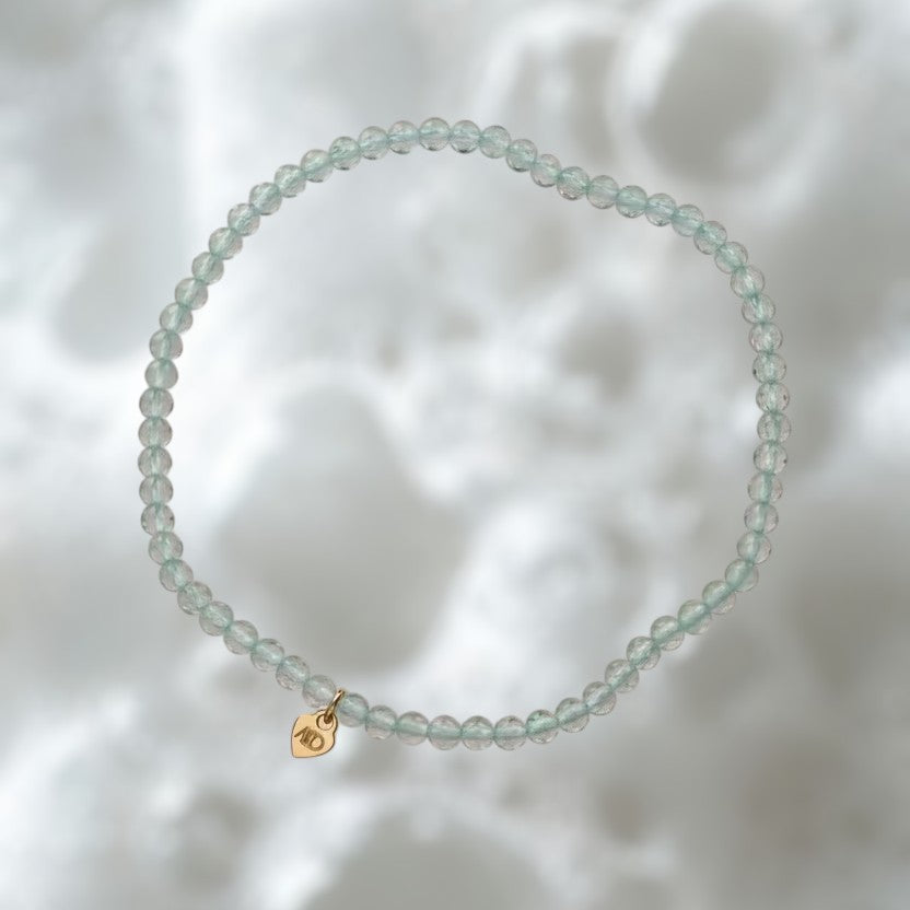 The Mermaid's Den Statice Sinensis Jade bracelet featuring 2mm translucent blue-green gemstone beads and a gold charm.