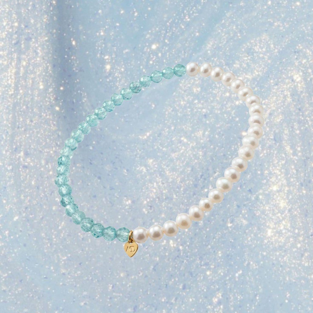 The Mermaid's Den Pearly Me bracelet featuring 3mm freshwater pearls and blue gemstones with a small gold heart charm.