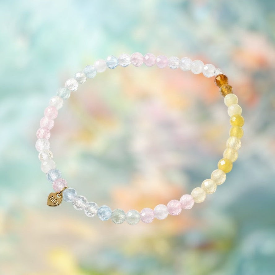 The Mermaid's Den Scabiosa bracelet featuring faceted rainbow gradient morganite beads and a small gold heart charm.