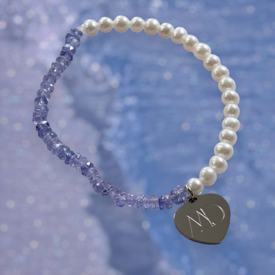 The Mermaid's Den Agapanthus bracelet featuring violet-blue Tanzanite beads, aquamarine pearls, and a heart charm.