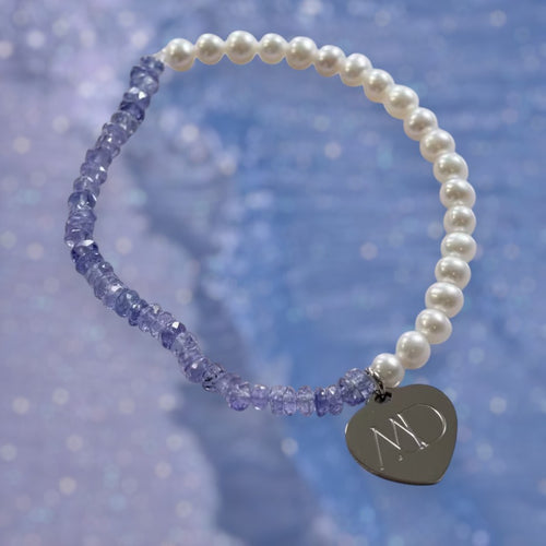 The Mermaid's Den Agapanthus bracelet featuring violet-blue Tanzanite beads, aquamarine pearls, and a heart charm.